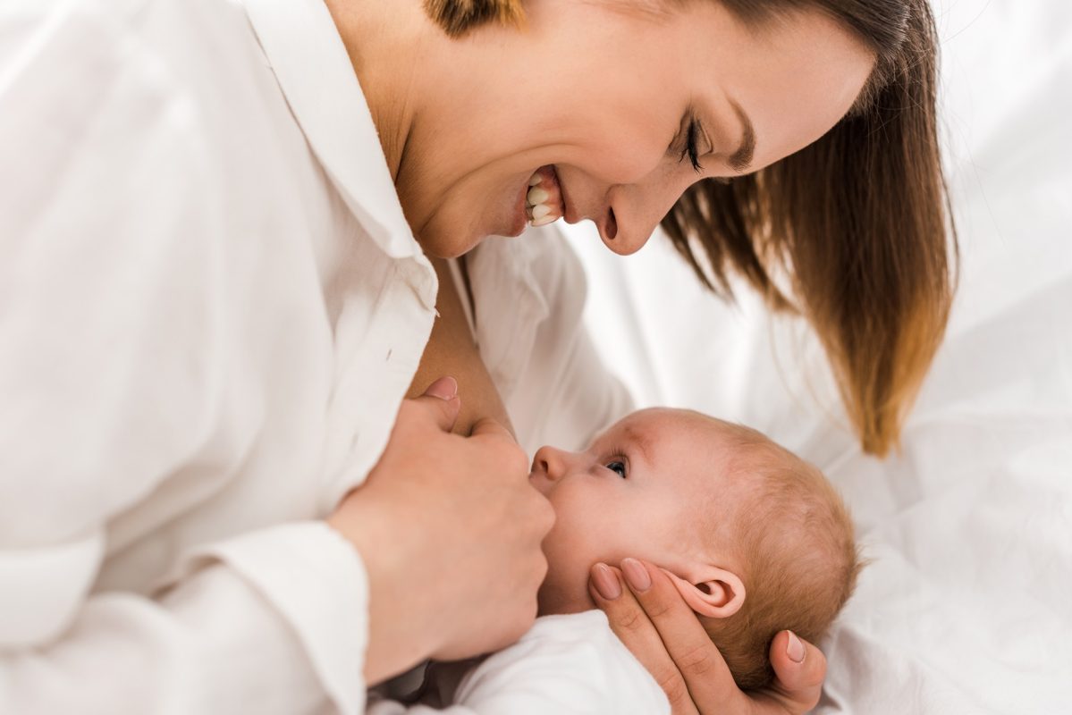 jeune-maman-souriante-en-blanc-t-shirt-alimentée-au-sein